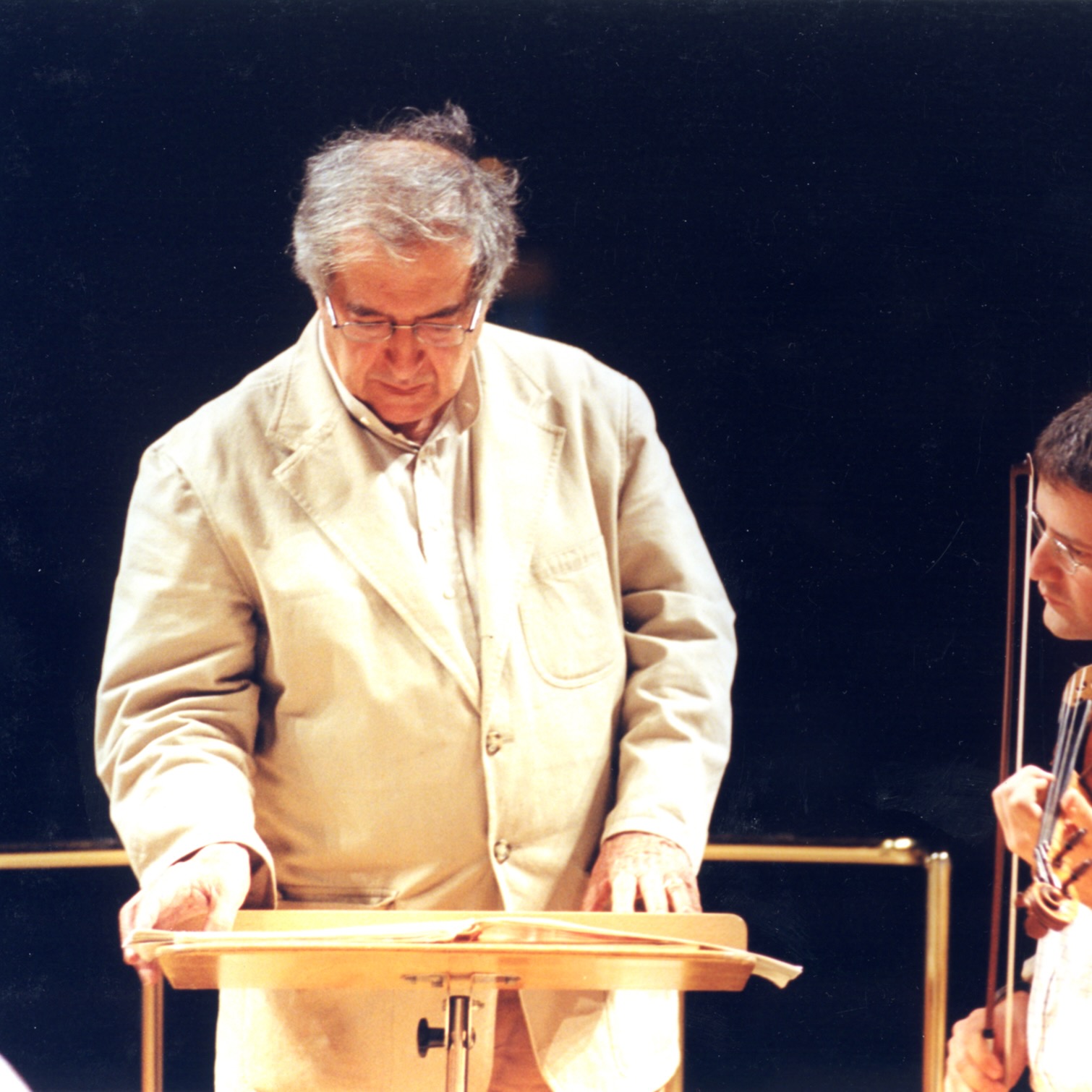 Luciano Berio standing at a conductor's podium looking at a score.