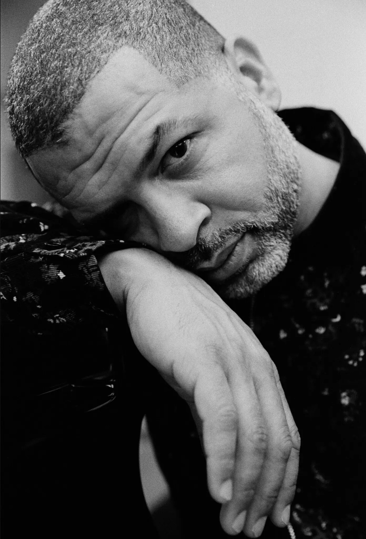 Jason Moran leaning his head on his wrist in a black and white photo.