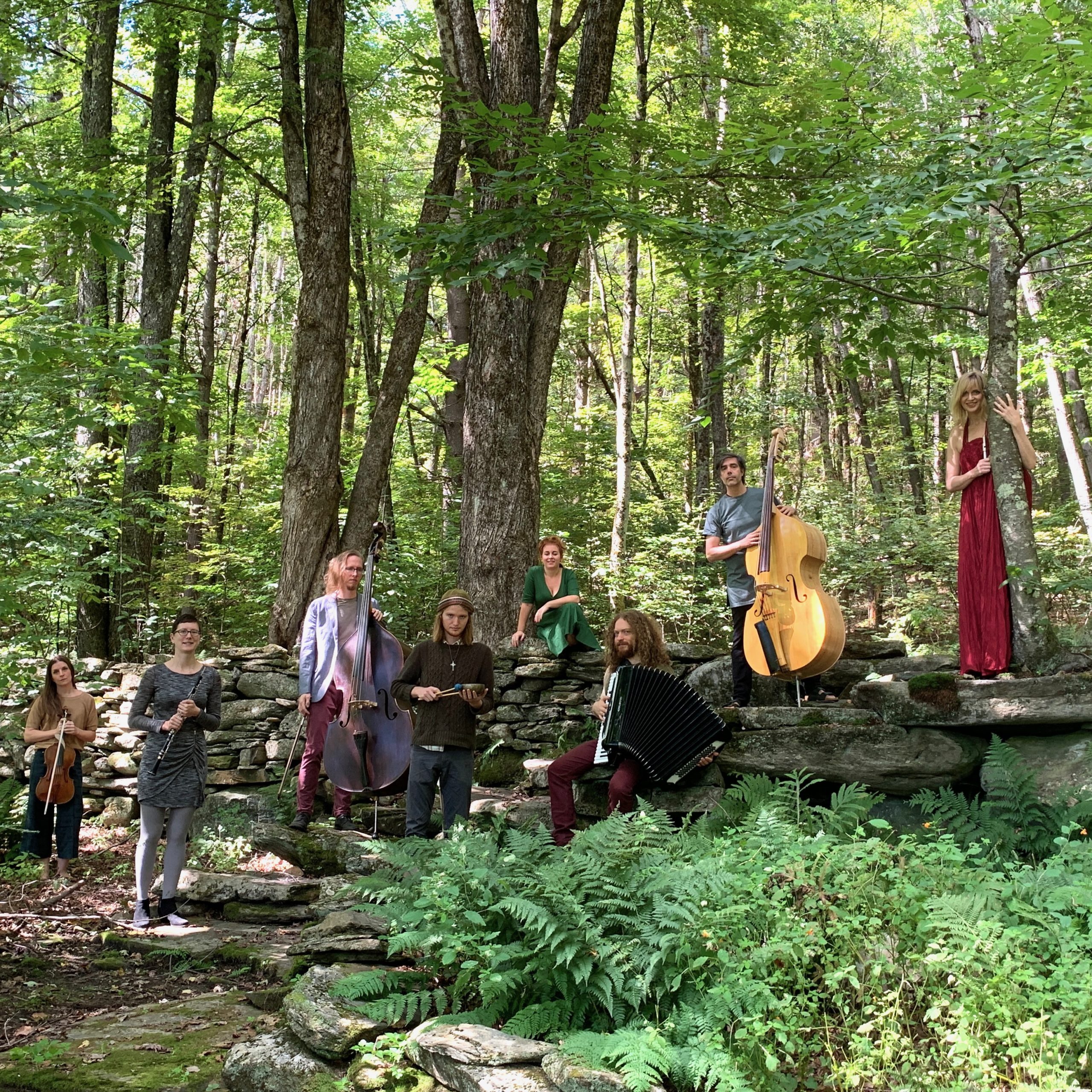 Ghost Ensemble posing in the woods with instruments.