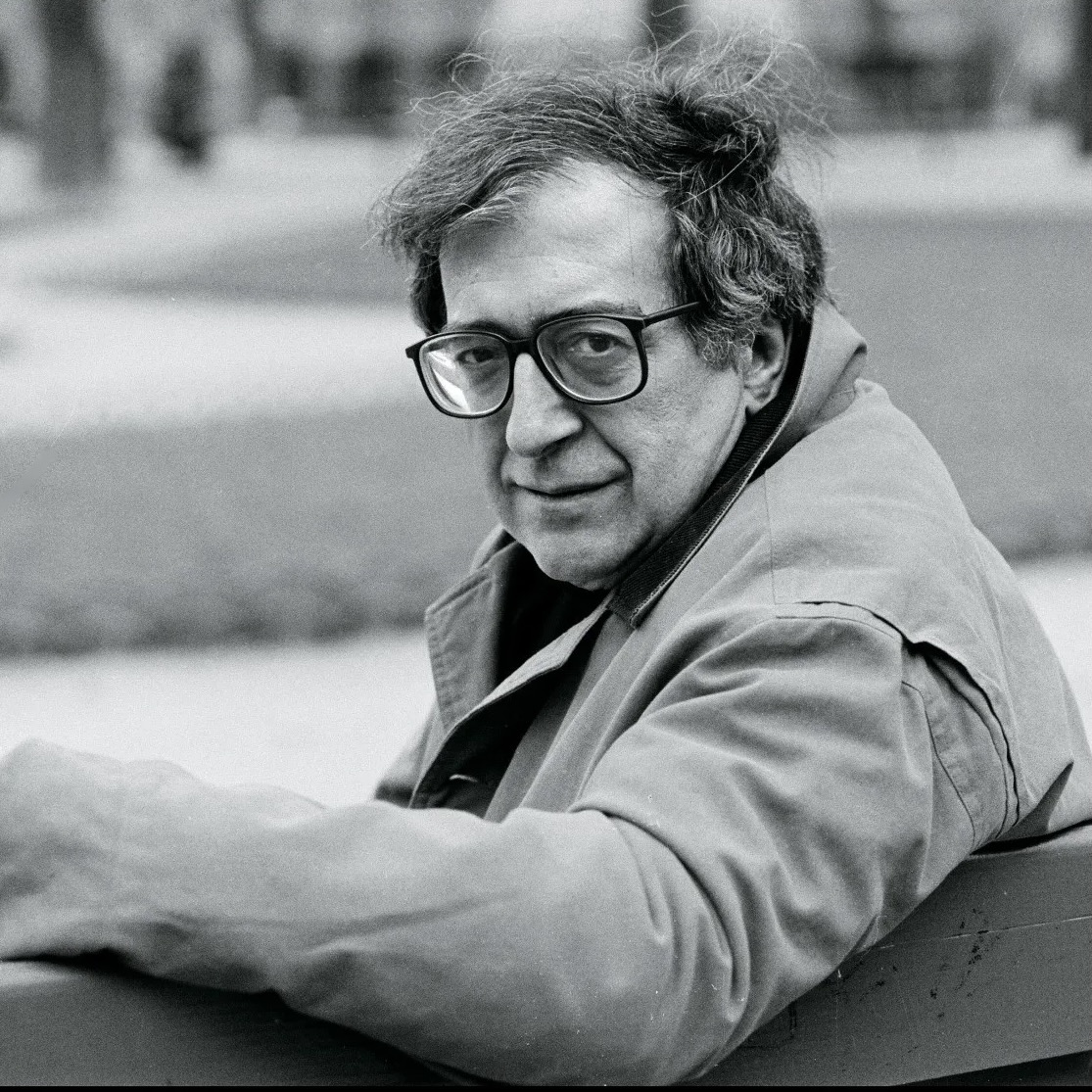 Luciano Berio sitting on a bench, head turned toward the camera.