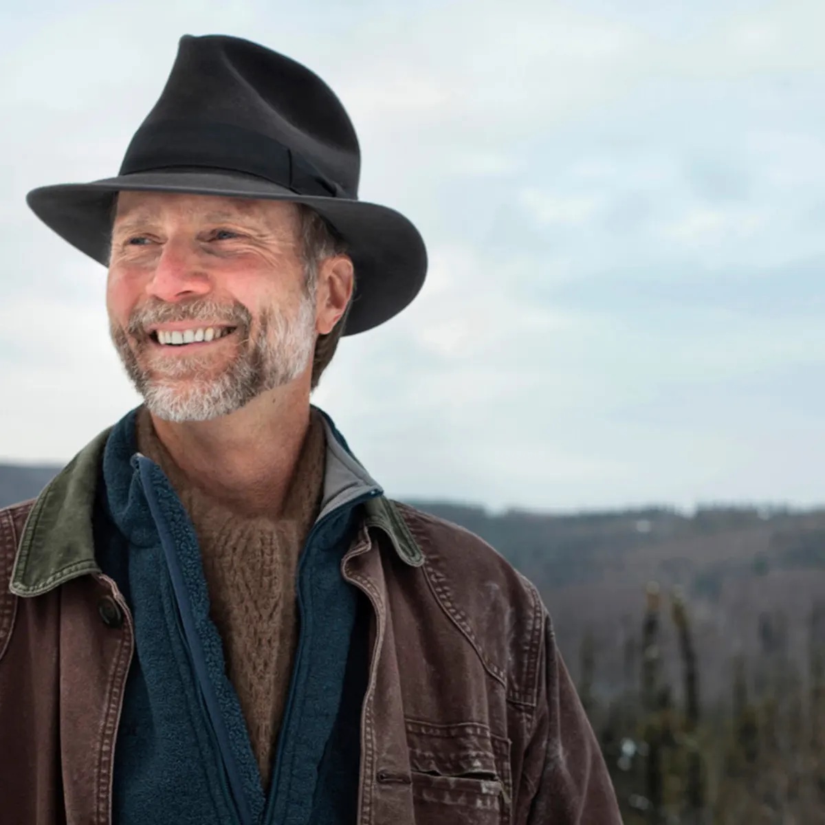 John Luther Adams smiling wearing a hat.