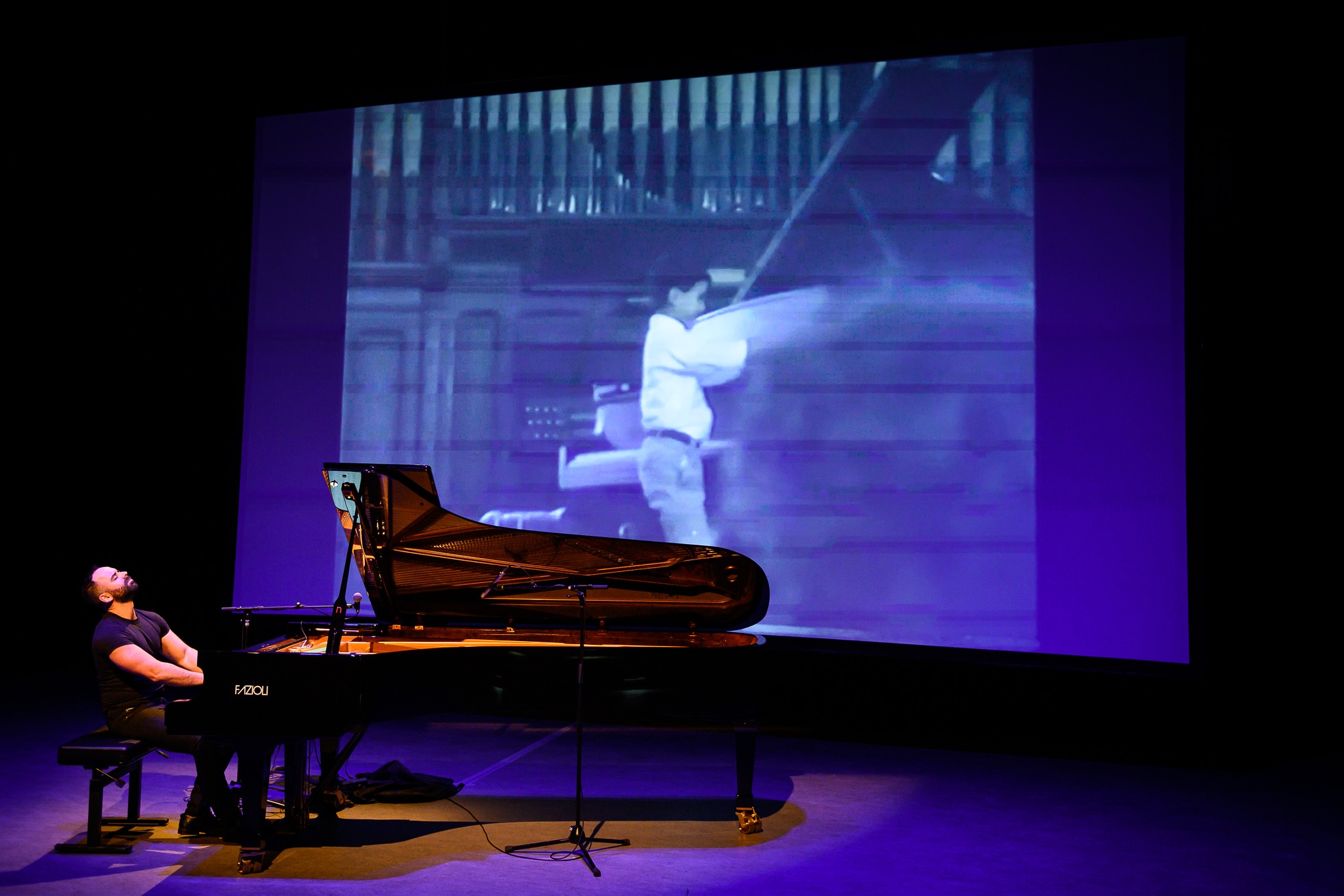 Adam Tendler playing piano in front of a projector.