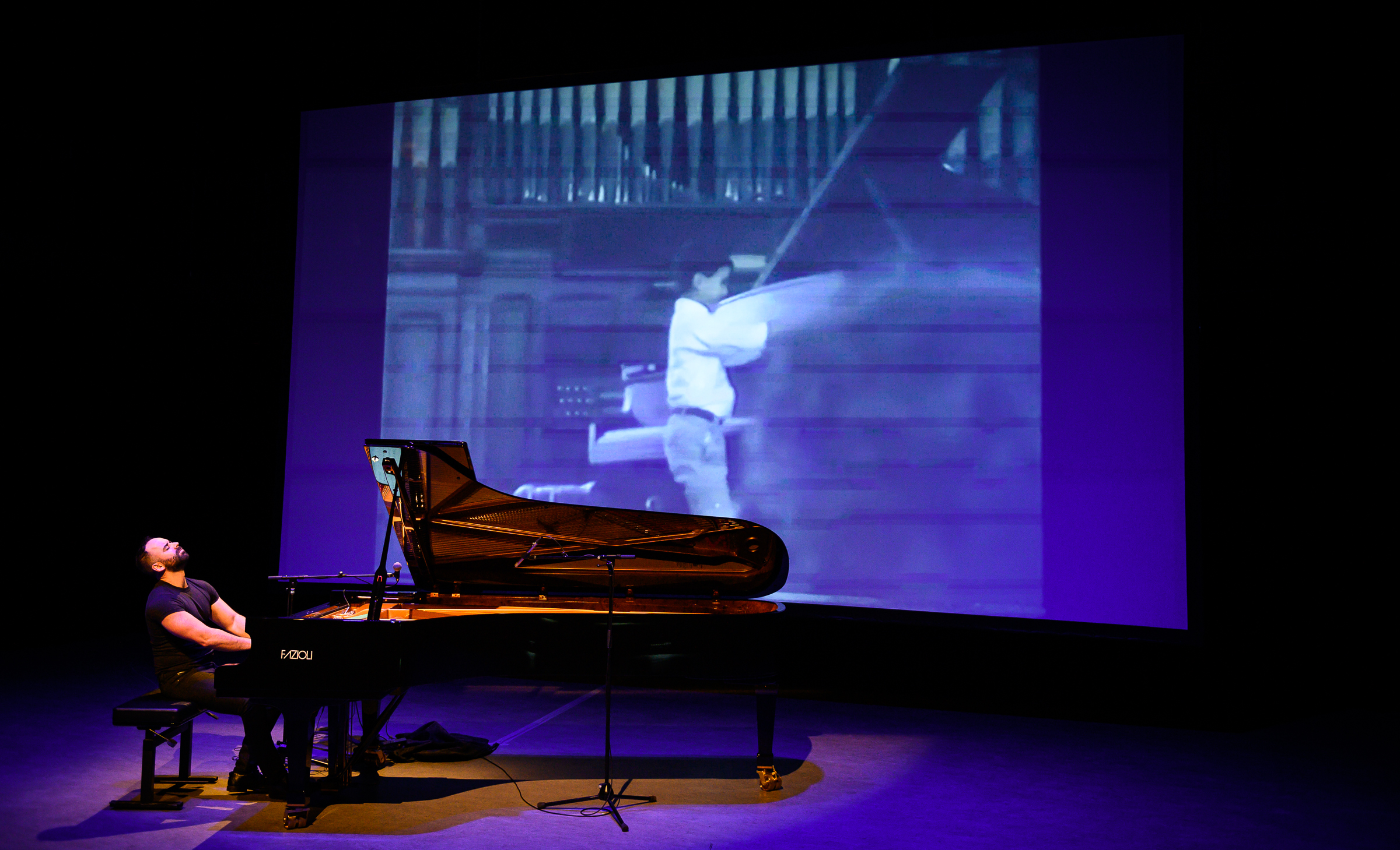 Adam Tendler playing piano in front of a projector.