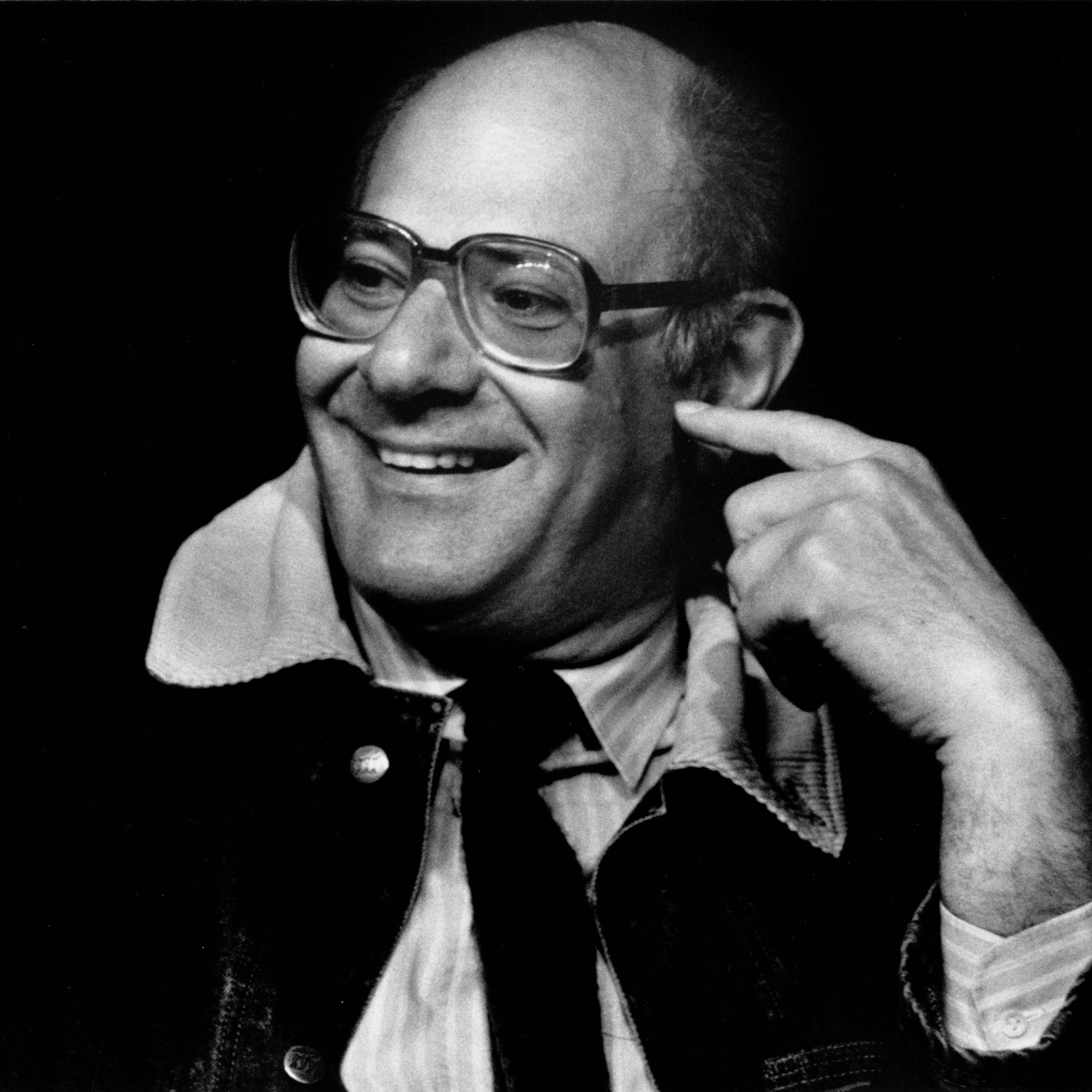 Black and white headshot of Mauricio Kagel holding a finger up to his face.