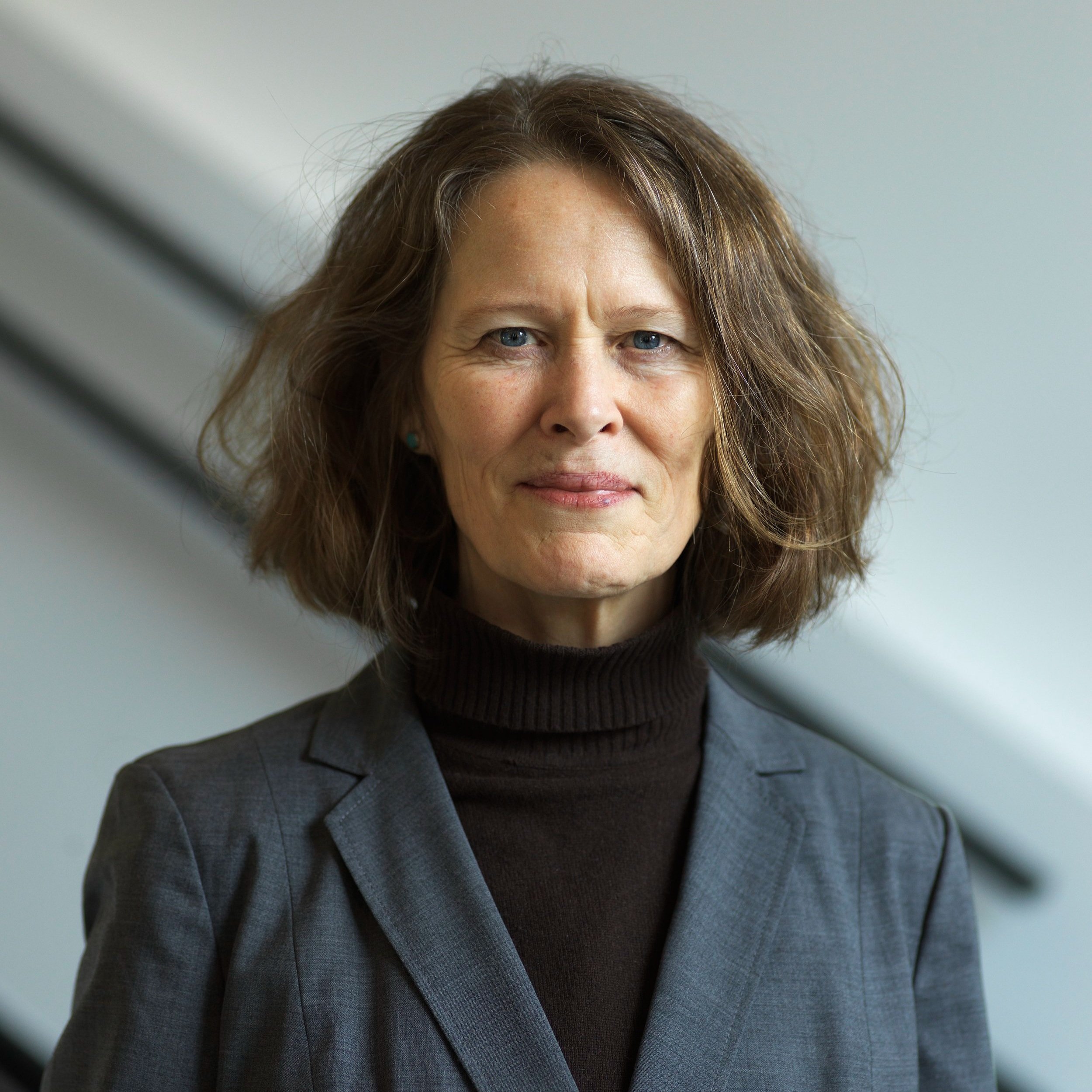 Kristin Norderval. Photo by Finserck Hanssen. A headshot of Kristin Norderval with shoulder length brown hair, a dark turtle neck, and a gray jacket.
