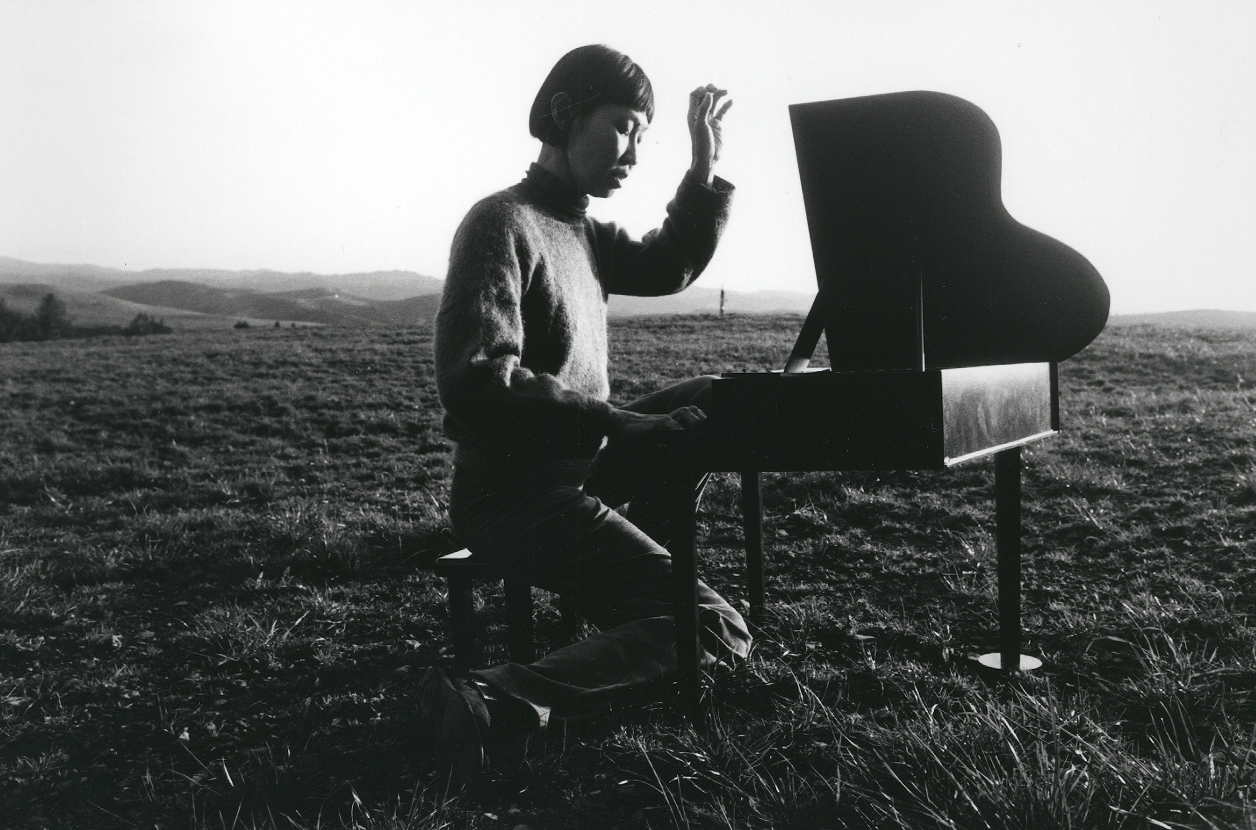 A woman in a field playing a toy piano.