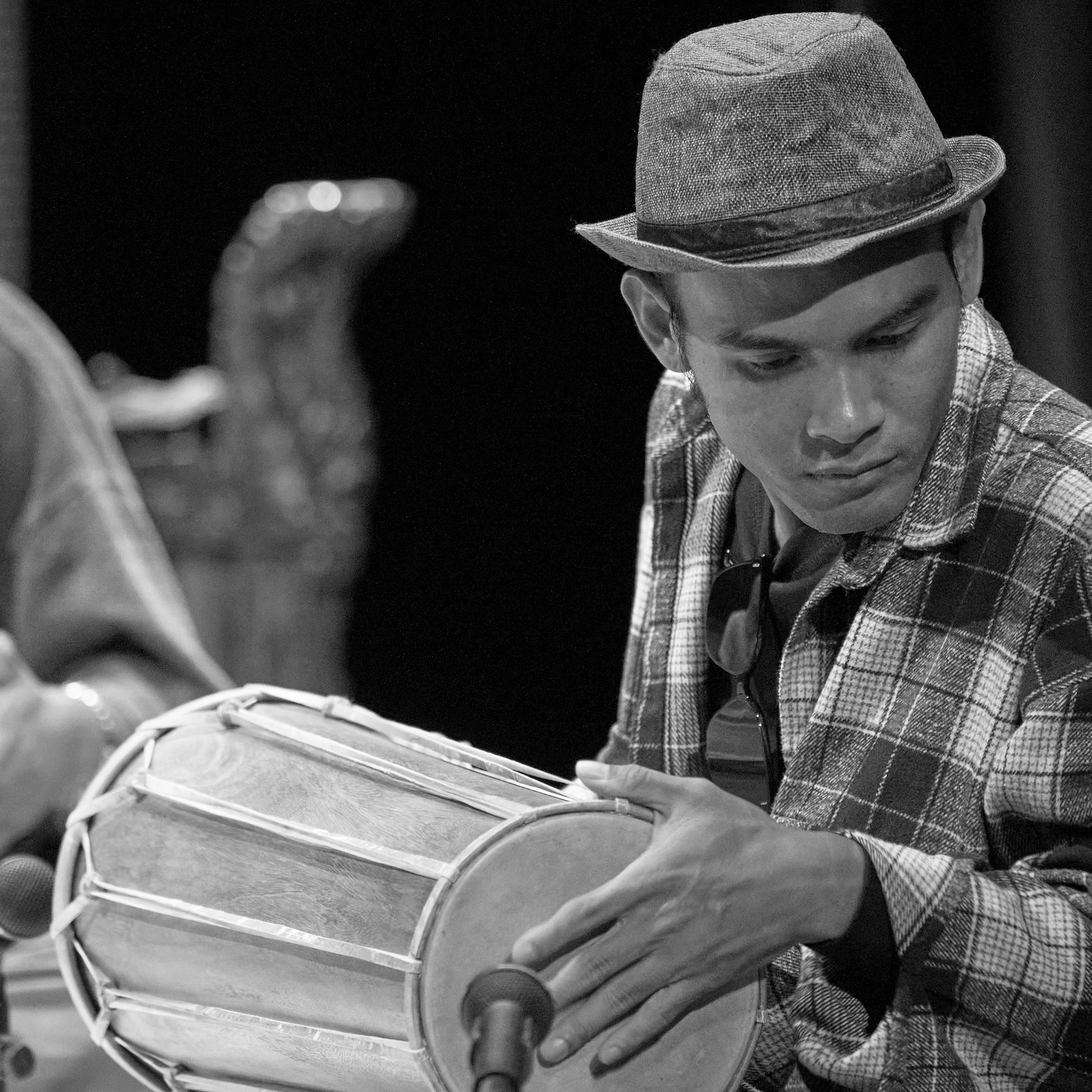 Putu Septa A man playing a double headed drum wearing a hat.