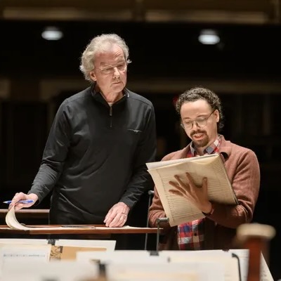 Tyler Taylor giving conductor notes while holding a large score.