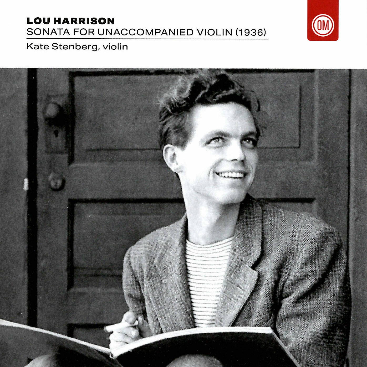 A b&w picture of a smiling man holding a book