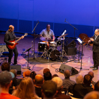 Liberty Ellman, Gerald Cleaver, and Ben Goldberg performing on stage.