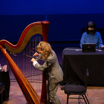 Zeena Parkins playing harp and Ikue Mori playing laptop.